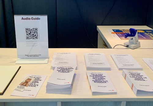 The audio guide is promoted through the visitor guide, ticket slip, and on screens behind the welcome desk.