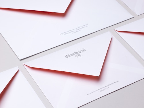 A set of different sizes enveloppes designed for Maison de Greef on a table