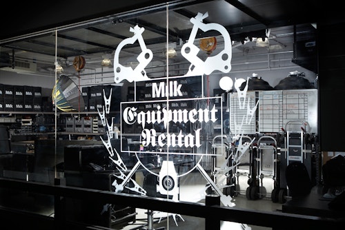 A window of an equipment rental workshop branded with the Milk logo